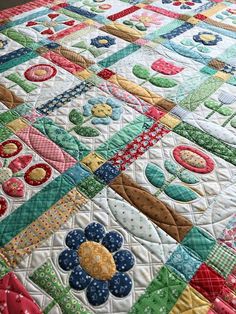 a quilted bedspread with colorful flowers on the top and bottom, sitting on a bed