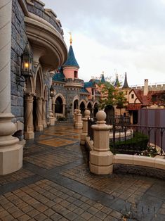 the walkway is lined with stone pillars and arches, leading to an elaborate castle like building