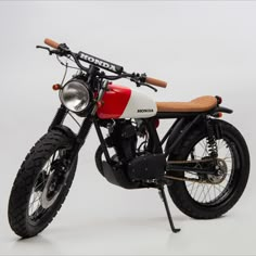 a red and white motorcycle parked on top of a white floor