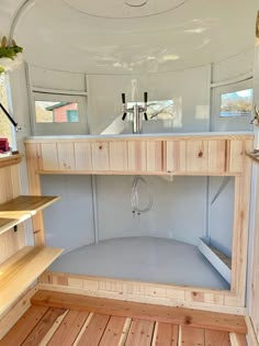 the inside of a van with wood flooring and shelves on each side that are built into the wall