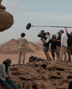 some people are filming in the desert with camera equipment and rock formations behind them,