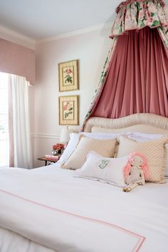 a bed with pink drapes and pillows on it