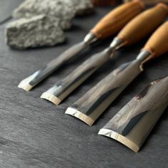 five different types of knives on a table with rocks and stones in the back ground