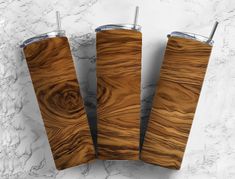 three wooden tumblers sitting next to each other on a marble counter top, one is made out of wood and the other has metal straws in it