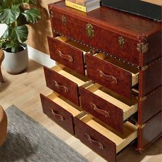 a wooden dresser with drawers on top of it next to a chair and potted plant