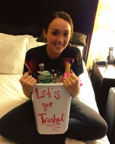 a woman is sitting on her bed holding a bucket with personal care products in it