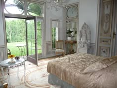 a bedroom with a large bed and french doors leading to the outside patio, along with an ornate chandelier