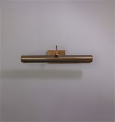 a metal object with a gold colored handle on a gray wall, hanging from the ceiling