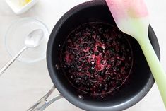 a bowl with berries and spoons next to it on a white tablecloth covered surface