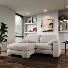 a white couch sitting on top of a wooden floor in a living room next to a window