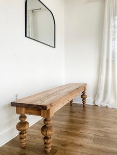 a wooden bench sitting on top of a hard wood floor next to a white wall