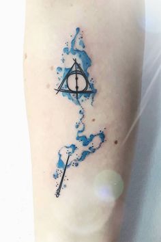 a harry potter tattoo on the left leg with blue ink splatters around it