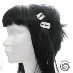 a white mannequin head with two black and white hair clips on top of it