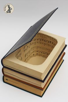 an open book with sheet music on it is sitting on top of several stacked books