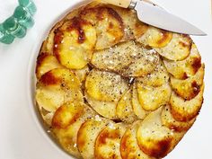 a white plate topped with potatoes covered in seasoning next to a knife