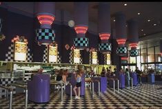 people are sitting at the checkered floor in front of some food court booths with lights on them