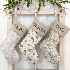 two christmas stockings hanging on a window sill with the words, mom and dad written on them