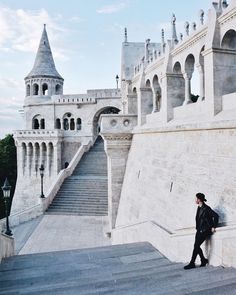 a man walking up some stairs next to a castle