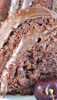 a close up of a piece of cake with chocolate frosting and cherries on a plate