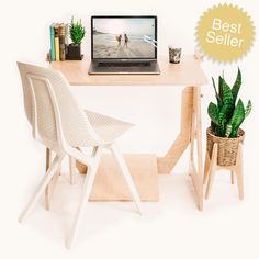 a laptop computer sitting on top of a wooden desk next to a potted plant