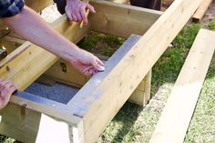 two people are working on some kind of wooden structure with their hands in the hole