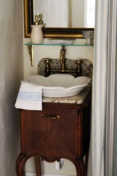 a bathroom sink sitting under a mirror next to a toilet paper dispenser