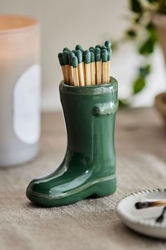 a green boot with matches in it sitting on a table next to a white plate