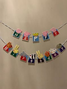 a birthday banner with animals and letters hanging from it's sides on a wall