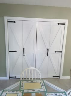 a white chair sitting next to a table with pictures on it and barn doors in the background