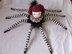 a doll with black and white stripes on it's body, sitting on a bed