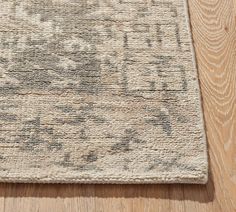 an area rug on the floor with wood floors and light colored carpeting in the background