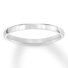 a white gold wedding ring on a plain surface, with the band slightly extended to the side