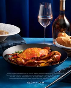 there is a crab and bread on the table next to two wine glasses, one bottle of wine and another glass of wine