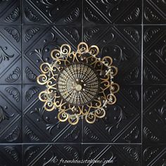 the ceiling is made up of black and gold tiles with an intricate design on it