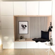 a room with white cabinets, black pillows and a painting on the wall above it