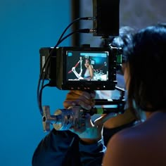 a woman holding a video camera up to her face while she is recording something on the screen