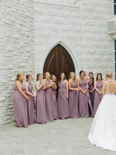 a group of bridesmaids standing in front of a church door with their backs to the camera