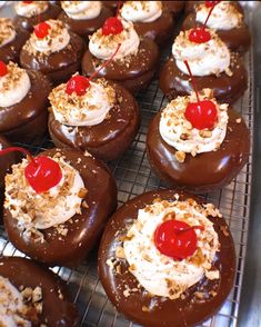 chocolate covered donuts with white frosting and cherries on top are sitting on a cooling rack