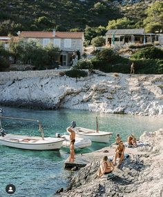 people are sitting on the rocks near boats