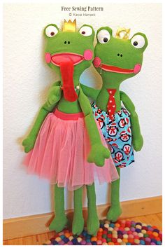 two stuffed frog dolls standing next to each other in front of a wall with candy