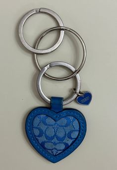 a blue heart shaped keychain hanging from a metal ring on a white surface