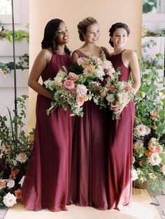 three bridesmaids in maroon dresses holding bouquets