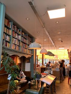 the interior of a bookstore with people standing and sitting at tables in front of bookshelves