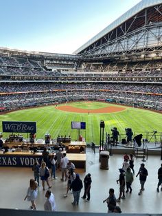 a baseball stadium filled with lots of people standing on top of a field next to each other