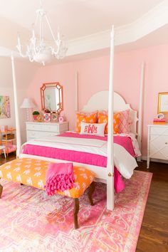 a bedroom with pink walls, white furniture and a chandelier hanging from the ceiling