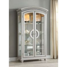 a white china cabinet with glass doors and silver trimmings on the bottom shelf