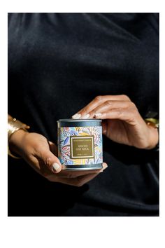 a woman is holding a candle in her hand and wearing a black shirt with gold trim