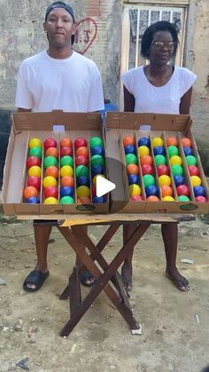 two people standing in front of a table filled with balls