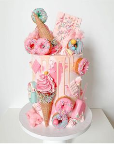 a pink cake with ice cream, donuts and other sweets on it's side