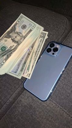 an iphone case sitting on top of a couch next to money